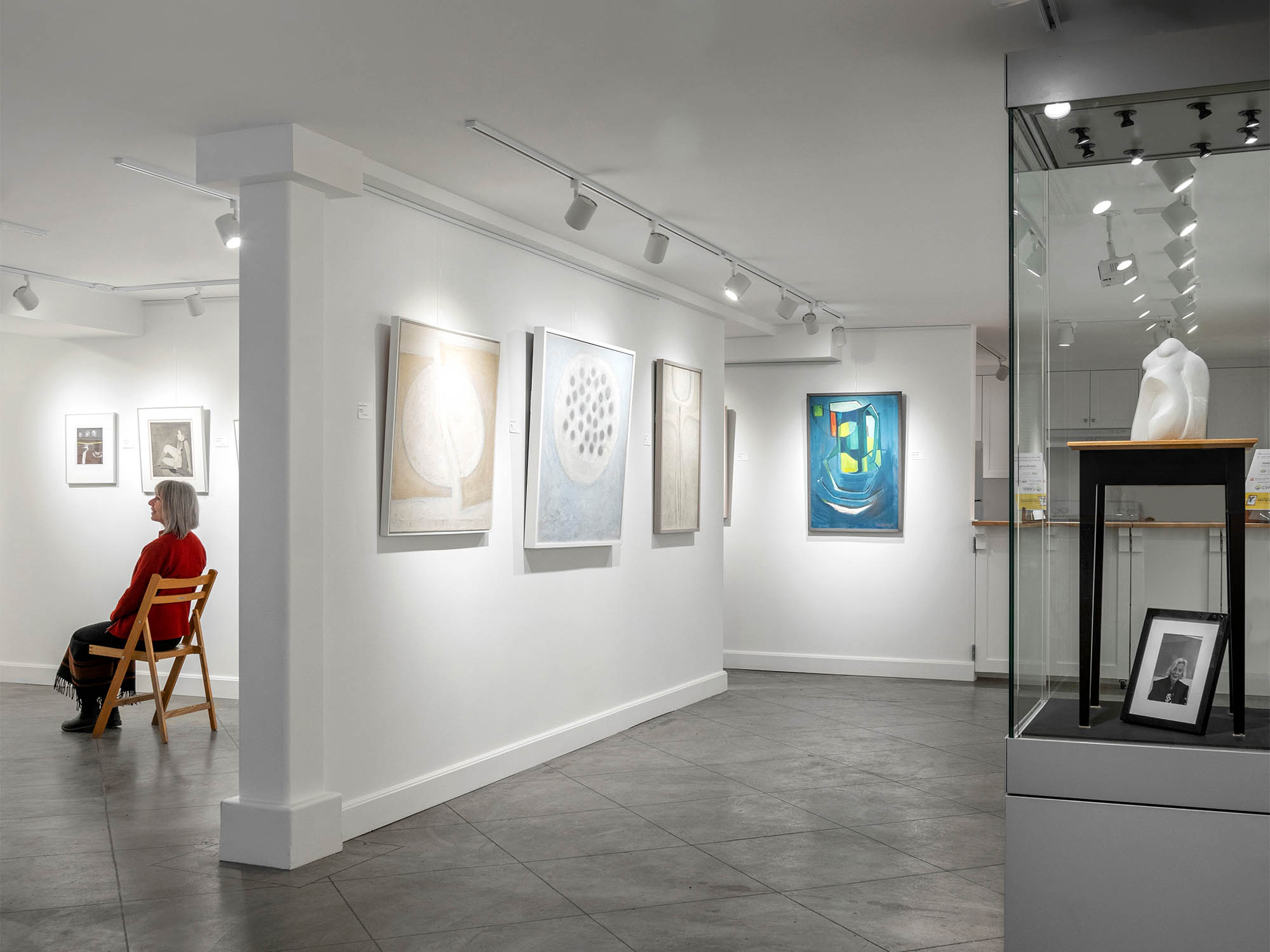 A woman sits in a bright art gallery, professional interior design photography.