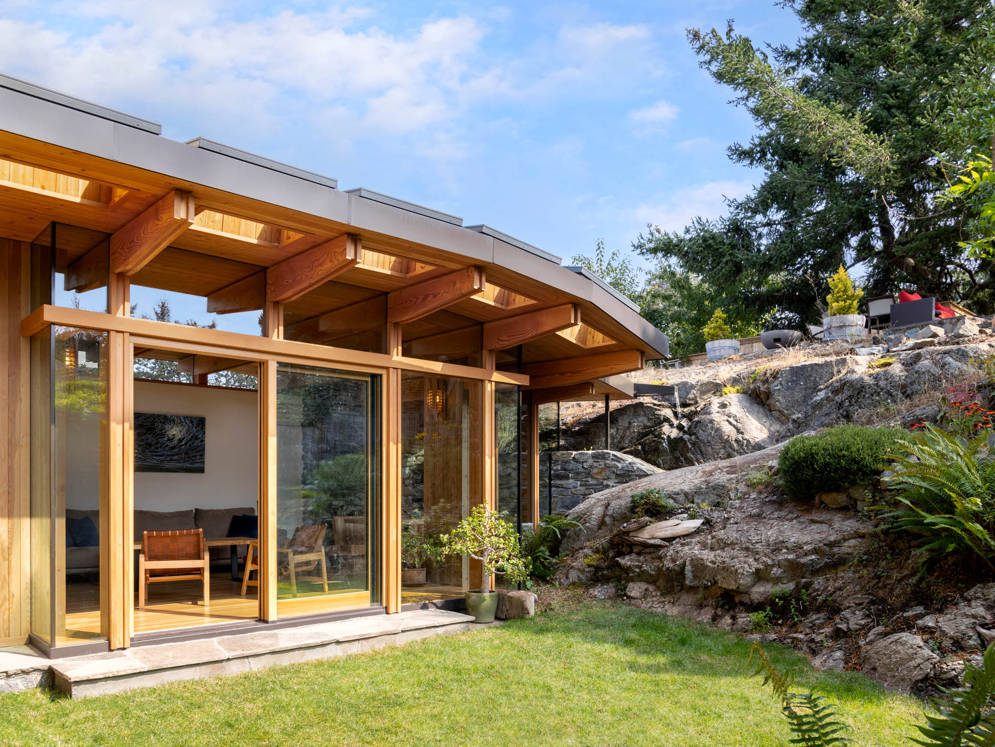 A bright and modern wood timber sunroom looks out at a naturally landscaped backyard.