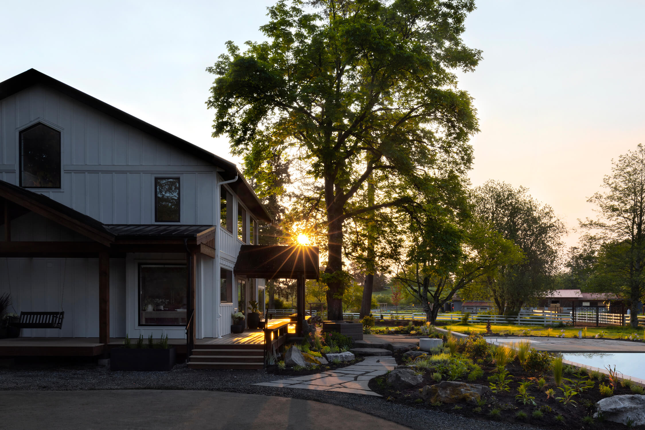 Sun sets on a modern farmhouse with natural native plant landscaping.
