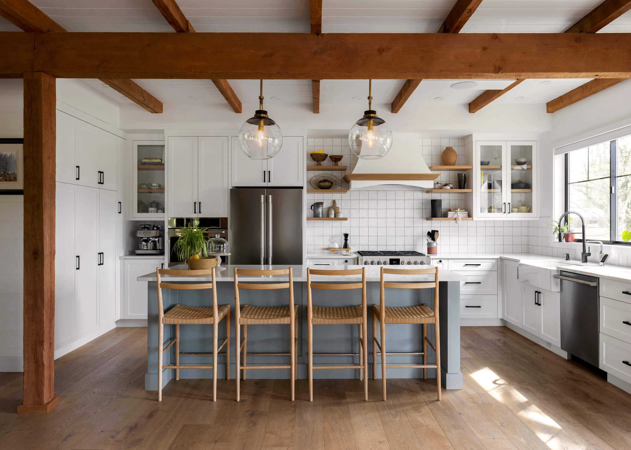 Exposed reclaimed wooden beams accent the newly constructed bright modern kitchen.