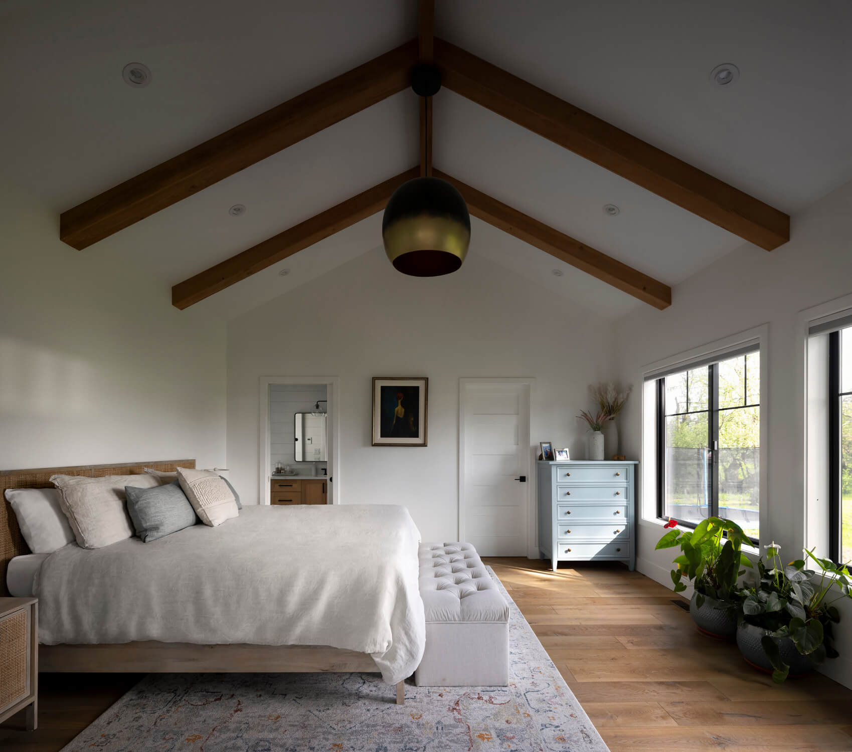 Reclaimed wooden beams featured in the ceiling of a bright modern bedroom.