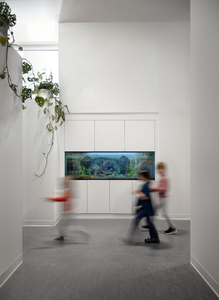 Children move past a built in wall aquarium, interior design photography by Tony Colangelo.
